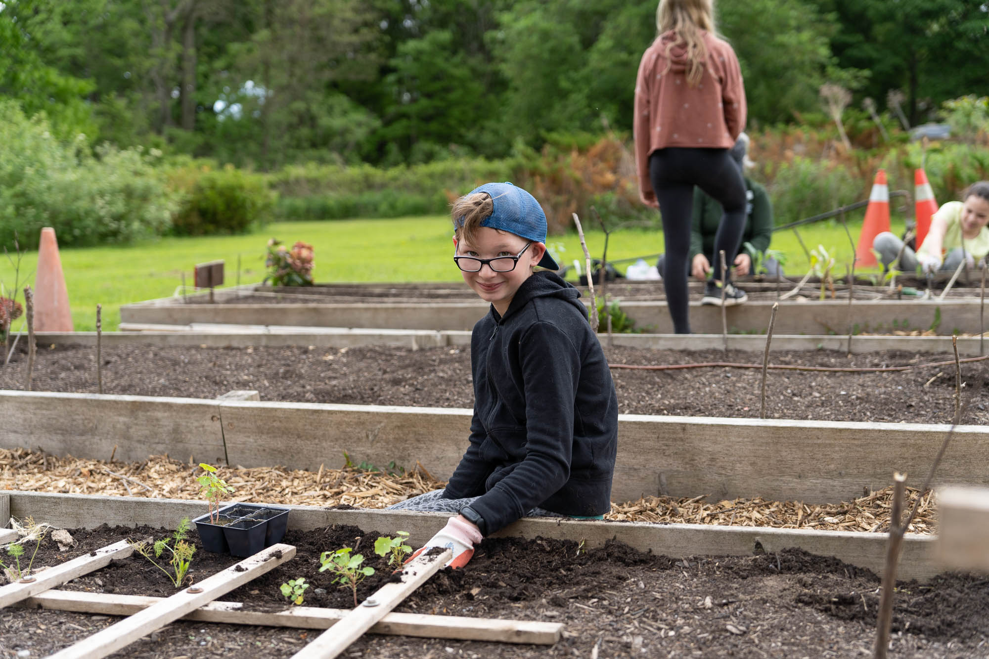 Child sitting with newly planted section of raised garden bed