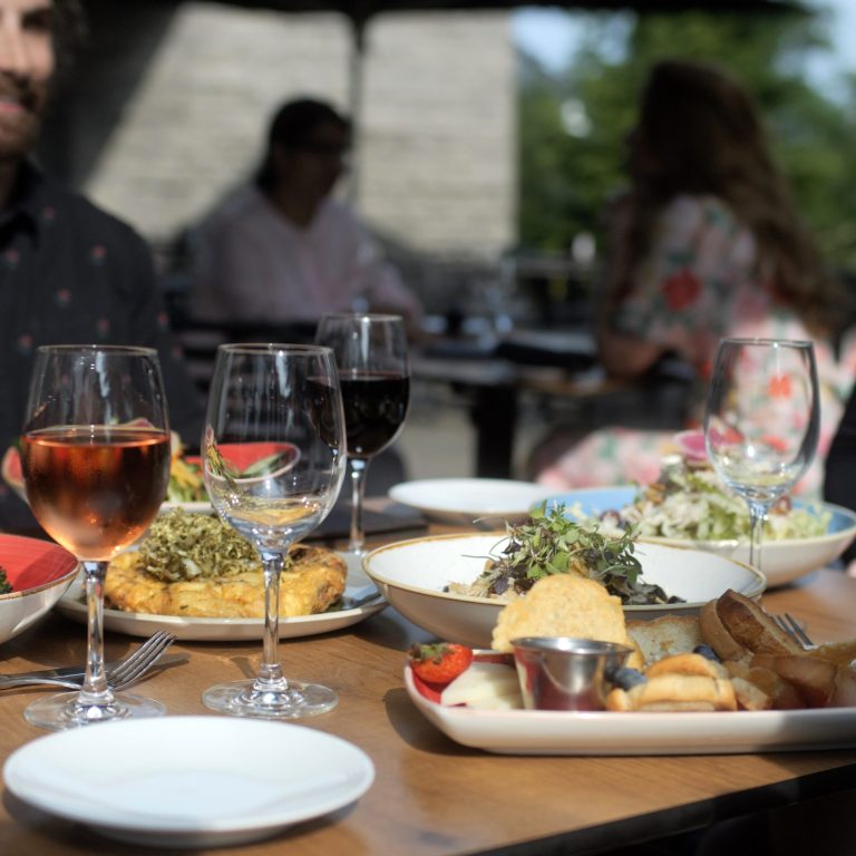 Sunny day on the rock garden bistro. table is filled with delicious looking food, drinks, and smiles on guests' faces