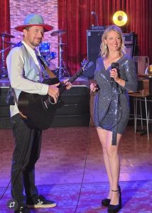 two performances performing on dance floor - man with a guitar and woman with a microphone
