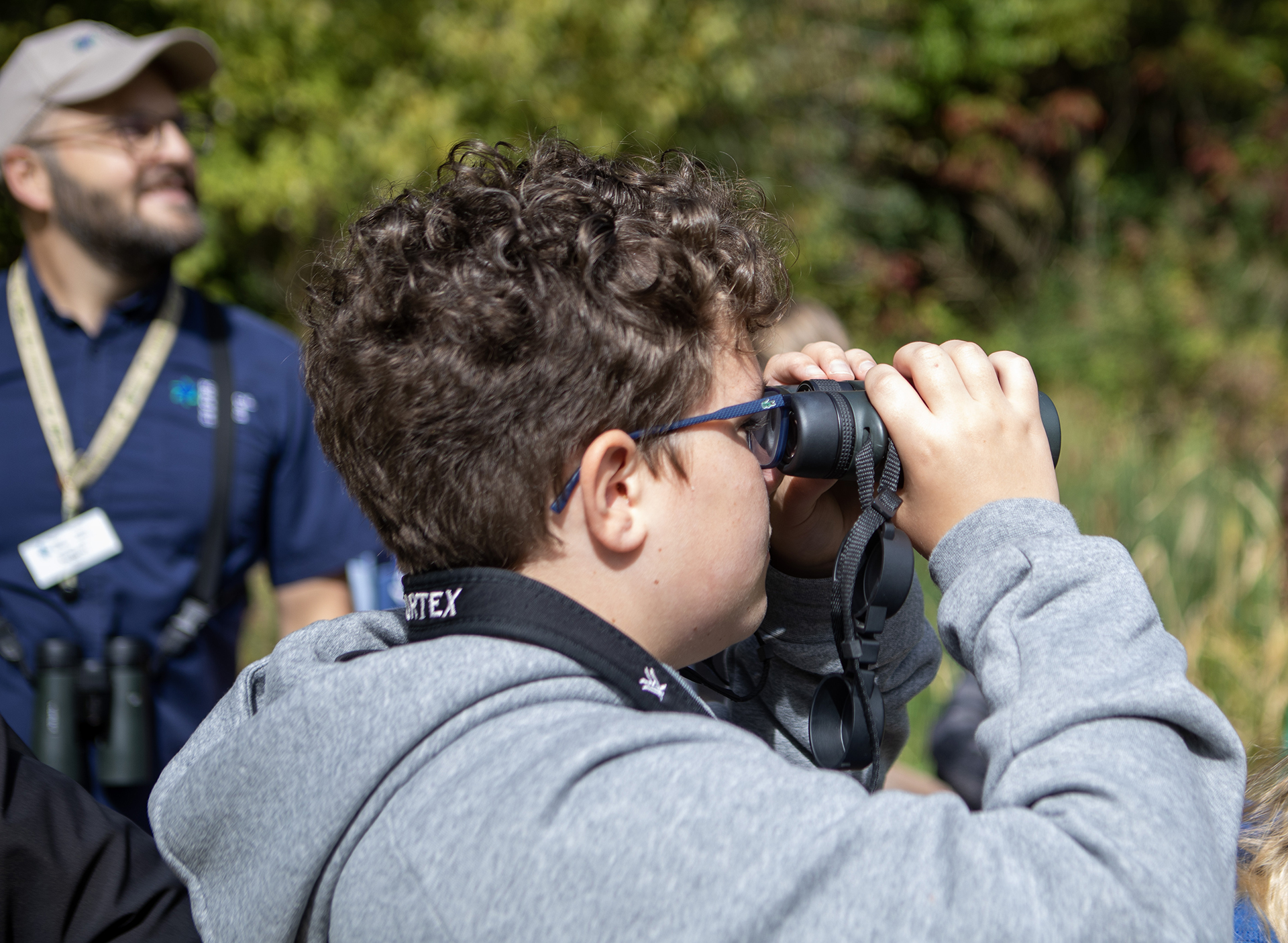 older child looking through binoculars on the nature trail