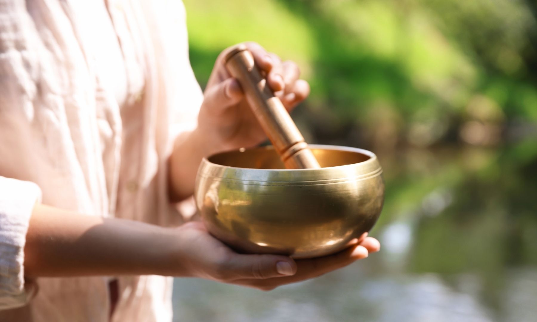 Hands holding a singing bowl outdoors in nature