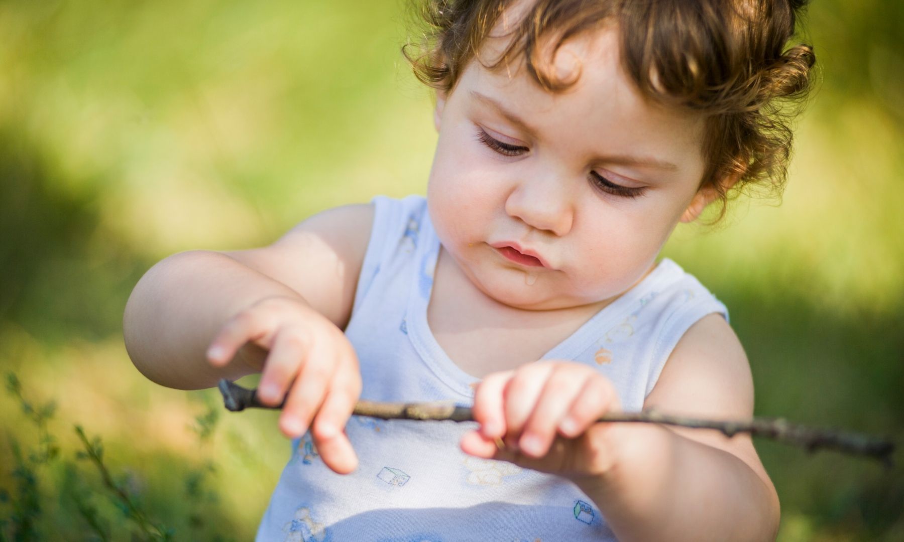 young child holding stick in a natural environment